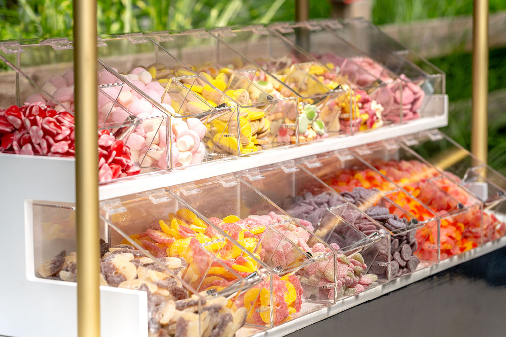 Assorted candies in clear bins on a display stand, with bright colors of red, yellow, orange, and pink.