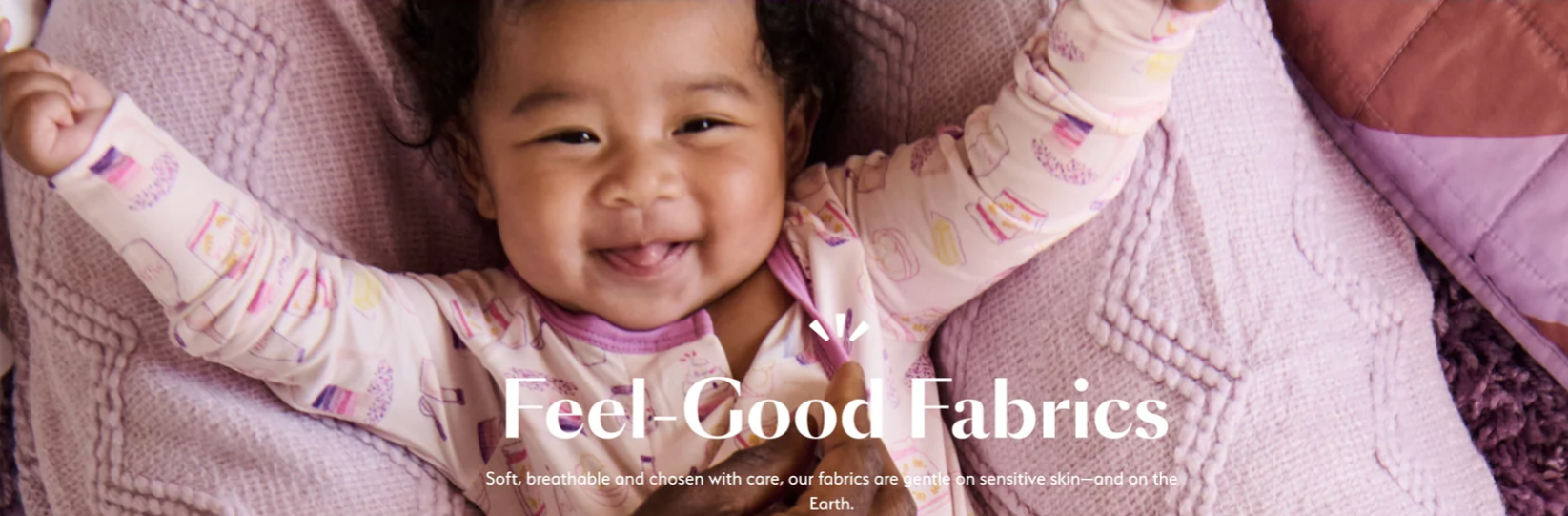 Smiling baby in pastel pajamas lying on a pink knitted blanket. Text: "Feel-Good Fabrics."