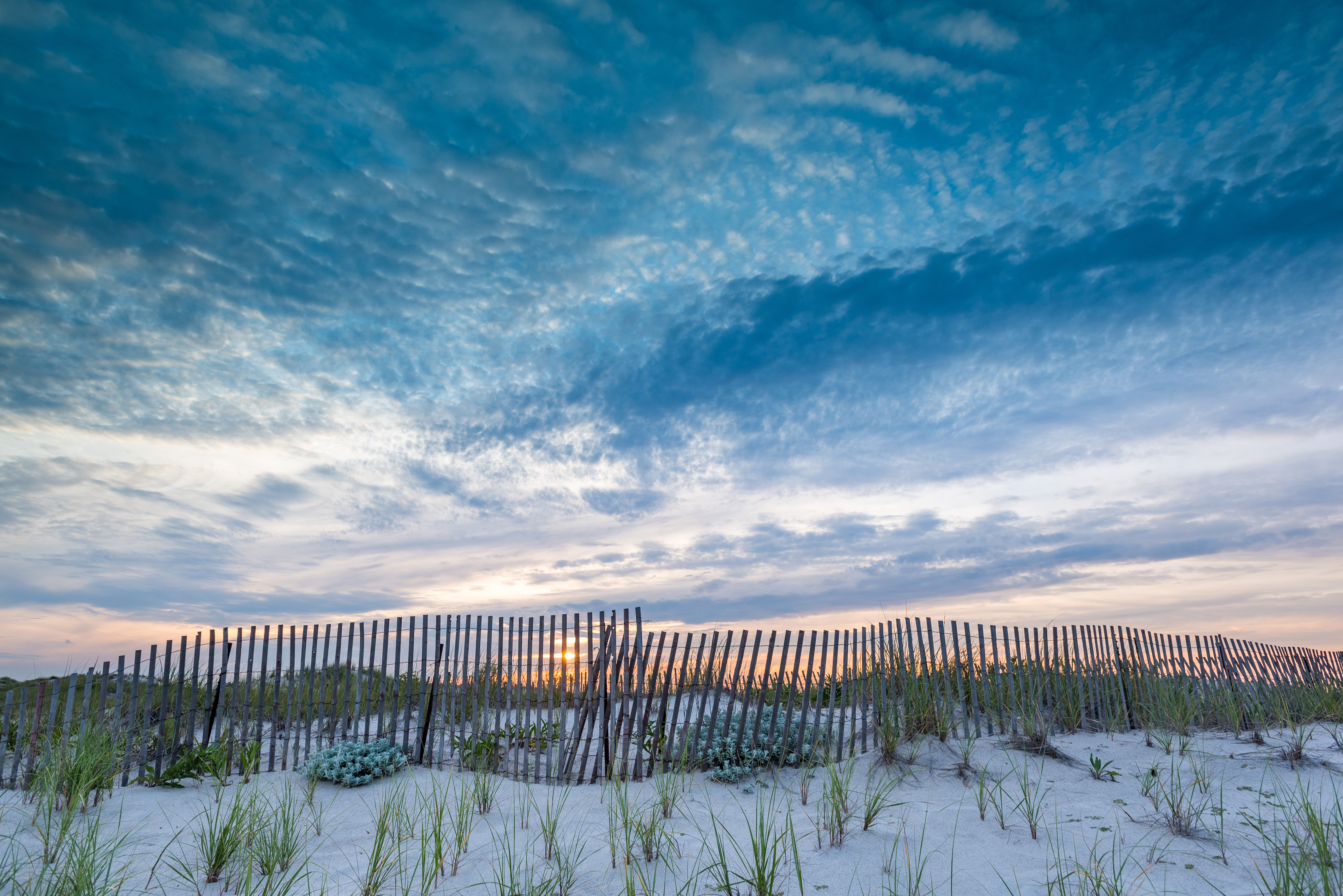 View of beautiful skyline behind wood fence surrounding Montauk beach line.