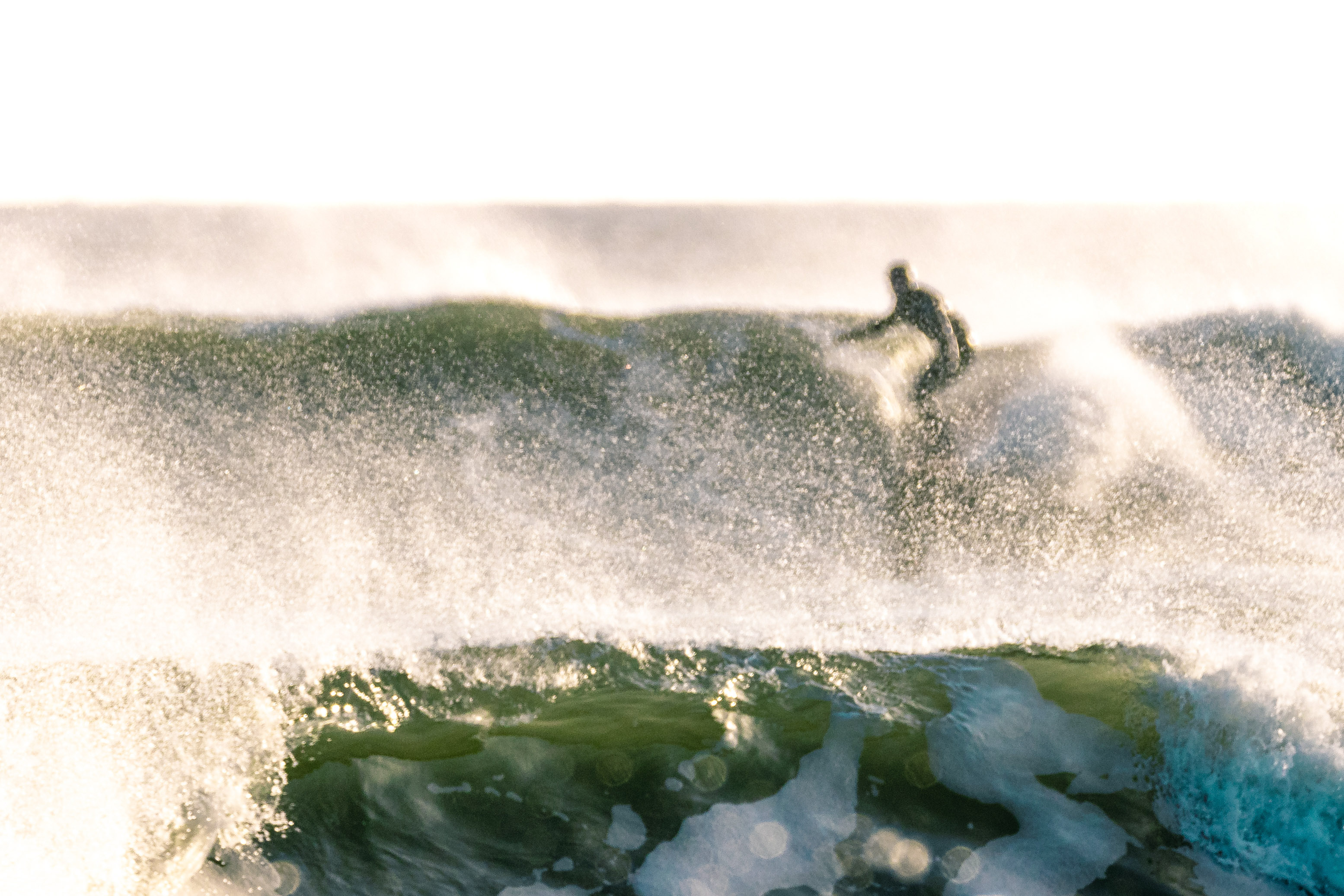 Man surfing on wave as wave crashes in front of him.