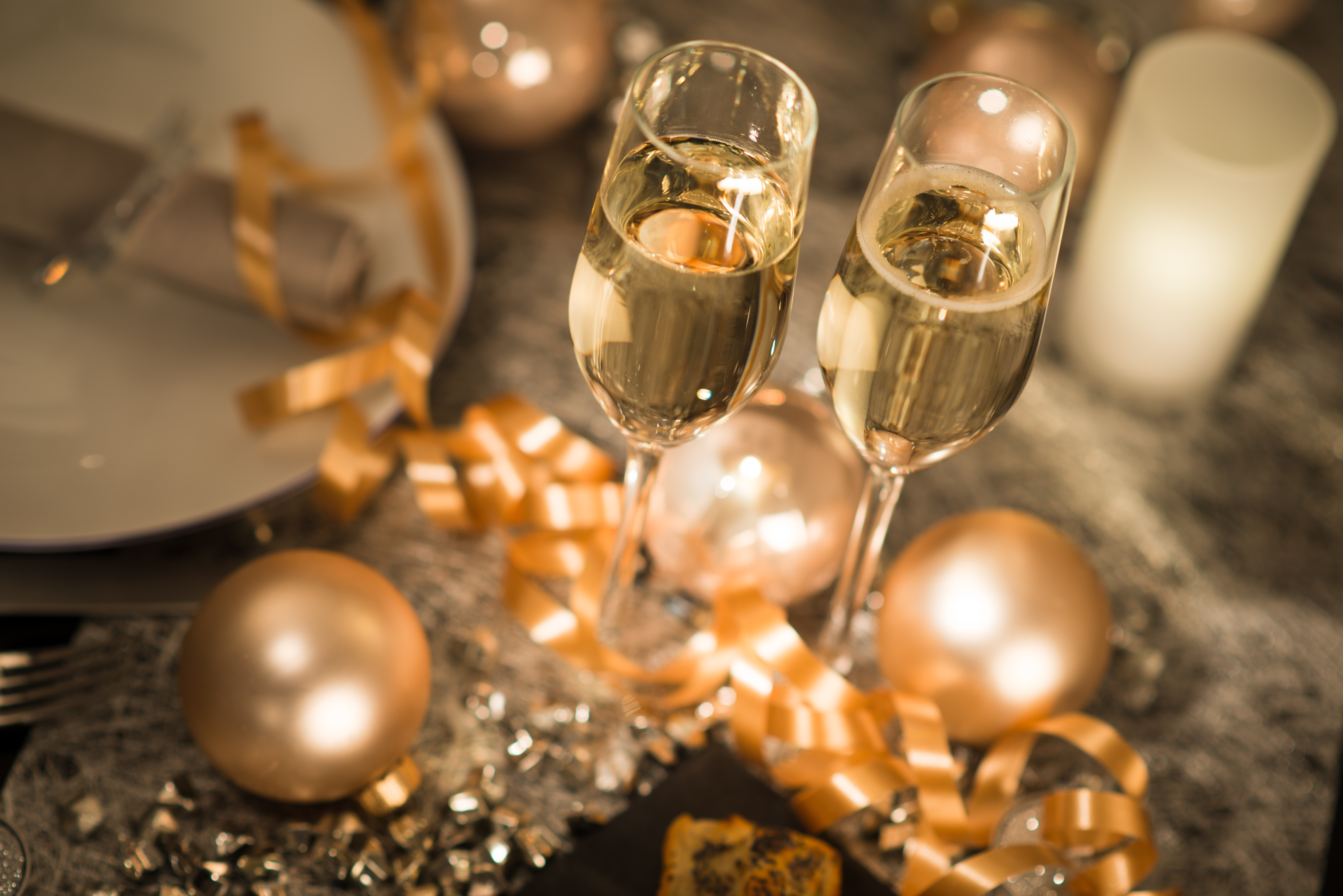 Two glasses of champagne surrounded by gold party decorations on a gold table cloth.