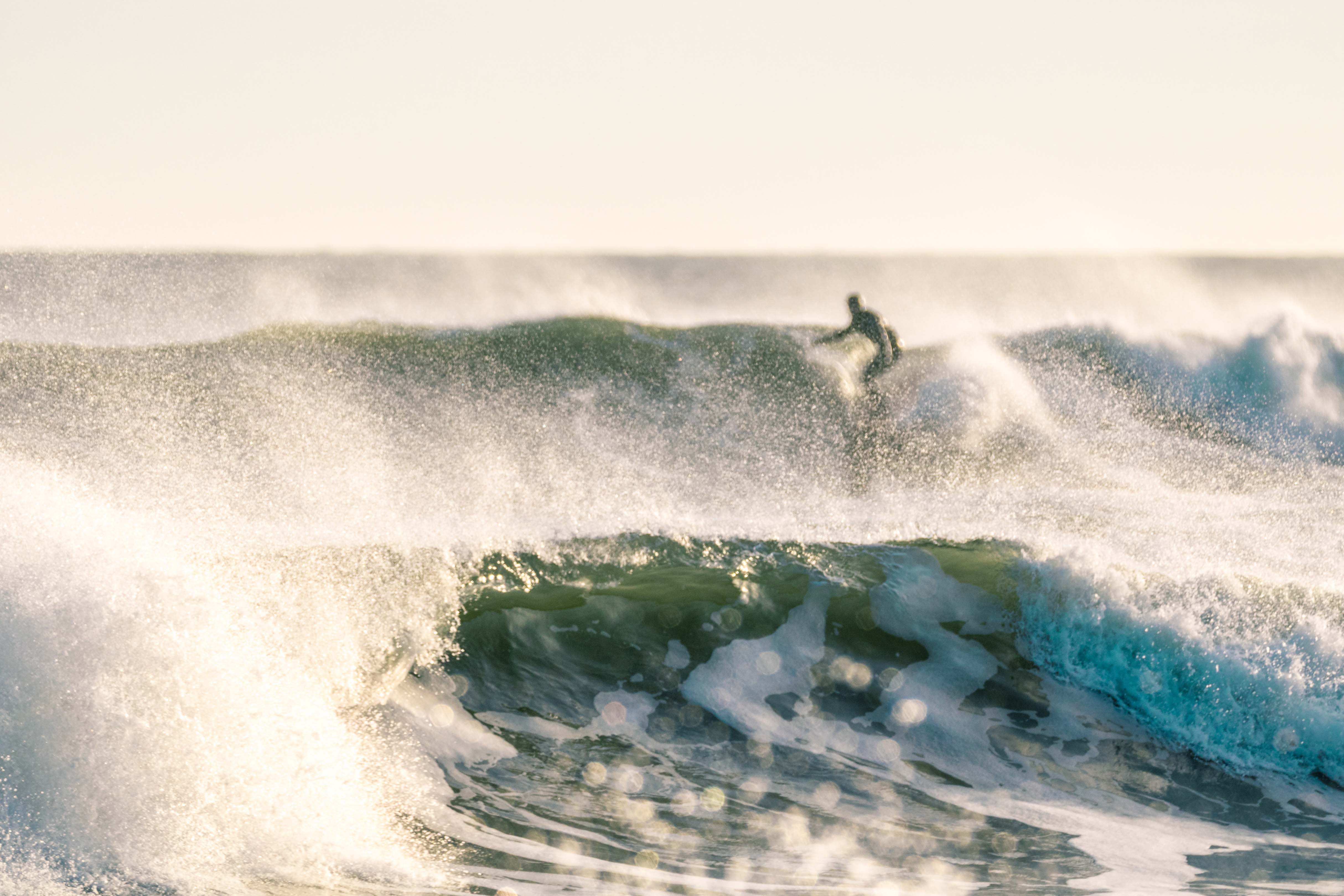 Man surfing on wave as wave crashes in front of him.