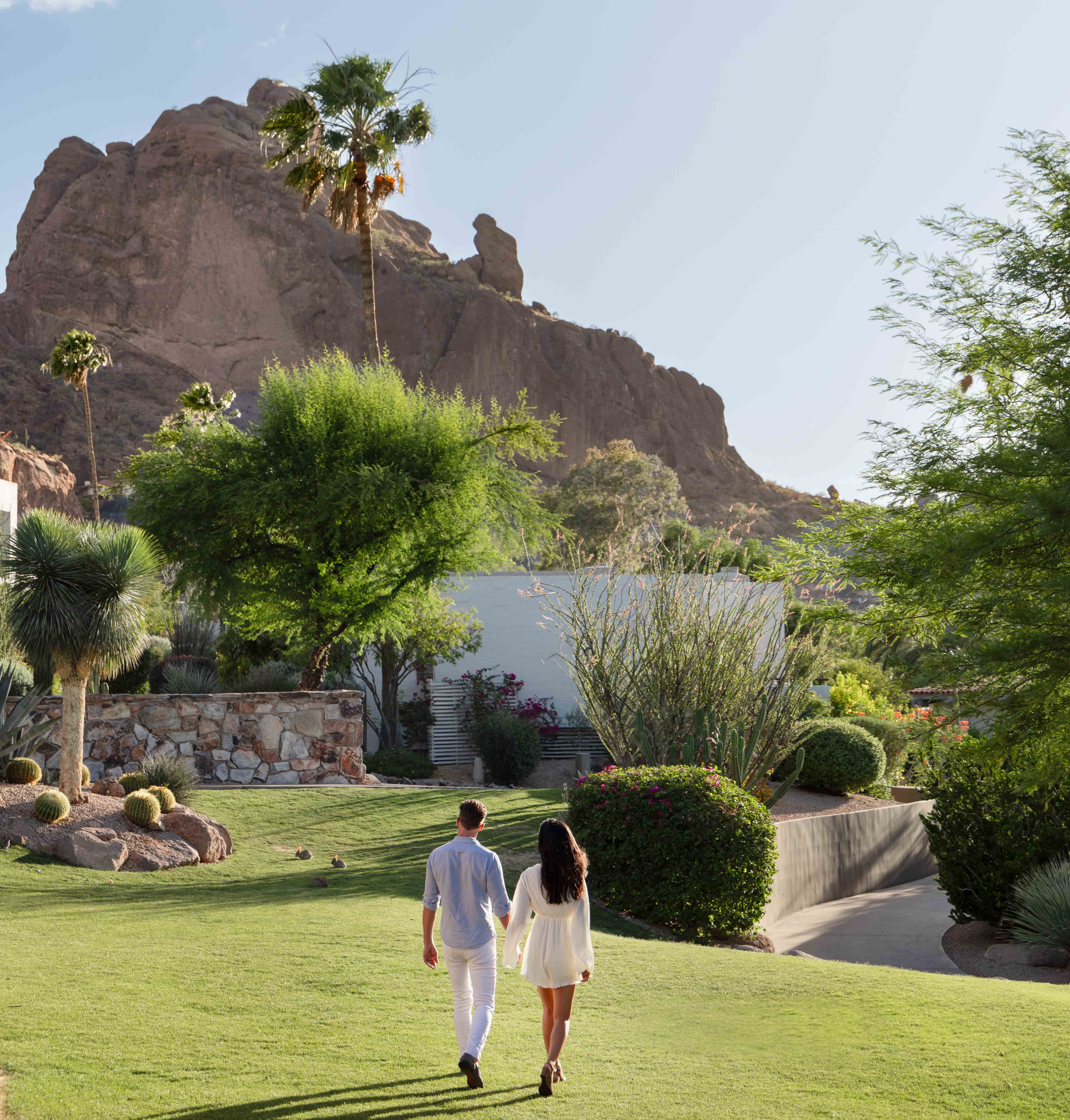 Couple holding hands walking through desert landscape with Praying Monk in background.