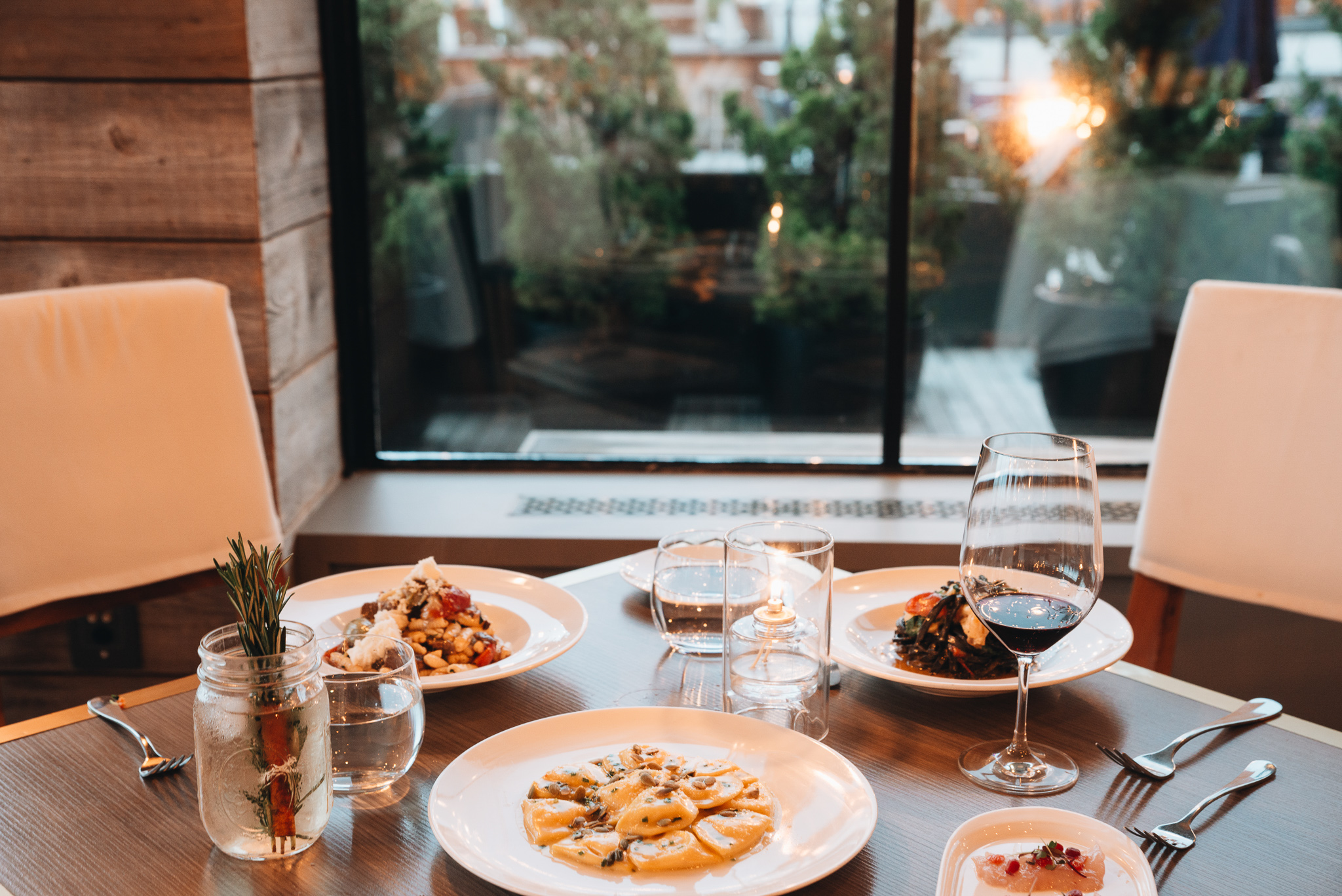 Table at Scarpetta Beach with an assortment of pasta and seafood dishes displayed with large window in background.