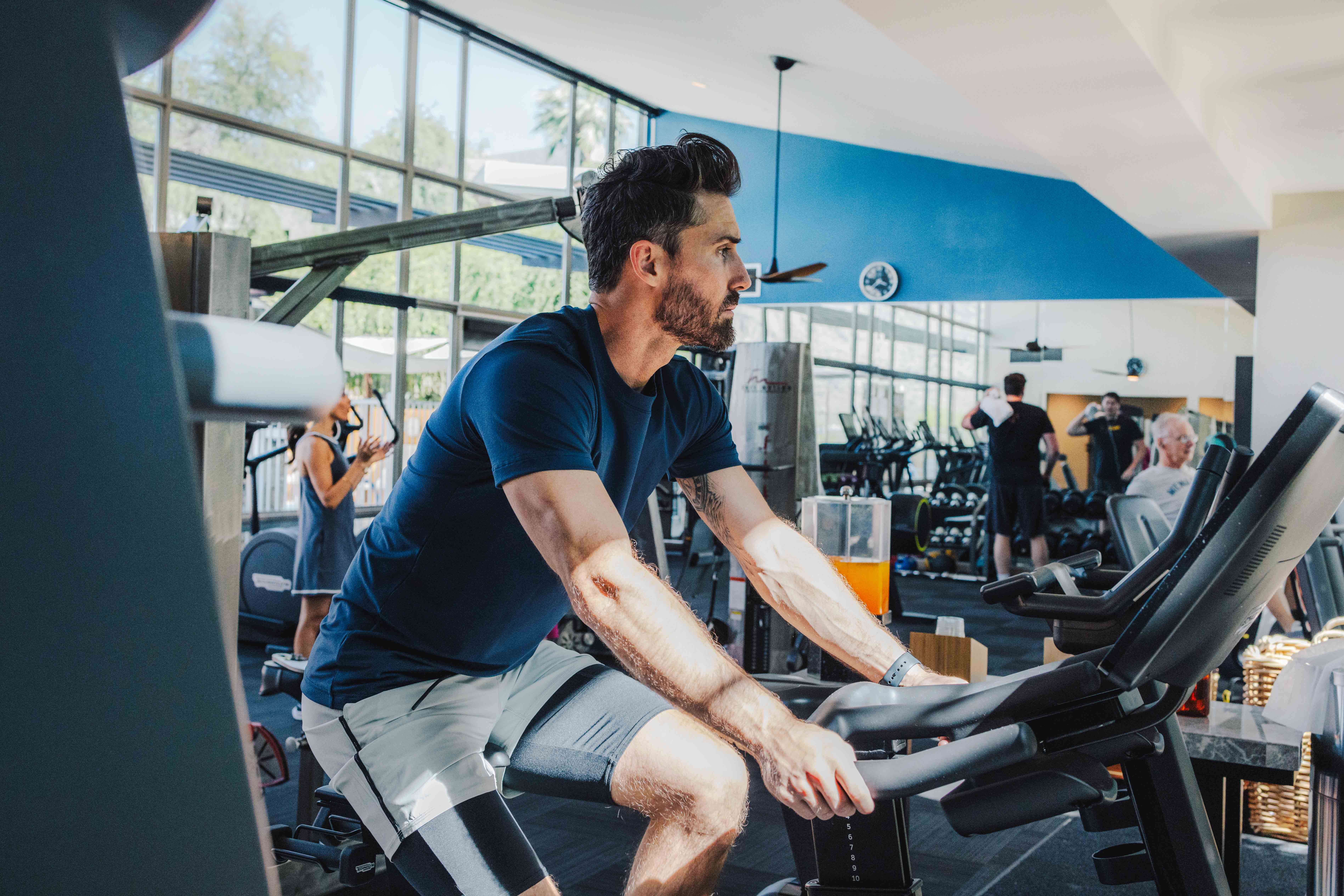 Man in fitness attire riding stationary bike in Sanctuary fitness center.