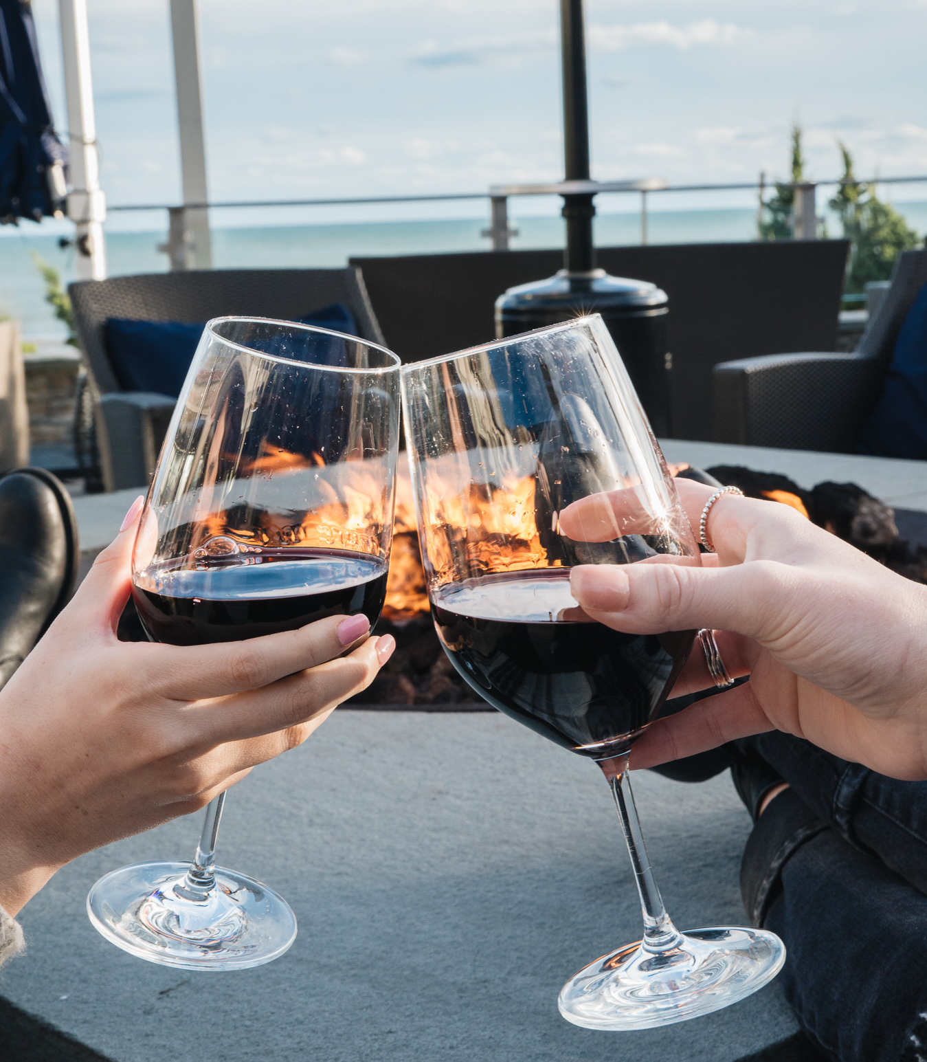 Two friends toasting red wine over the firepits at Gurney's Montauk.