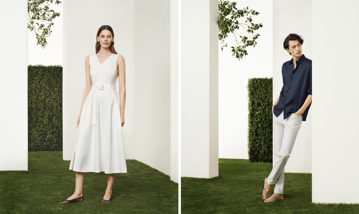 A woman in a Theory white dress and a man in a Theory dark shirt and white pants posing separately among trimmed hedges.