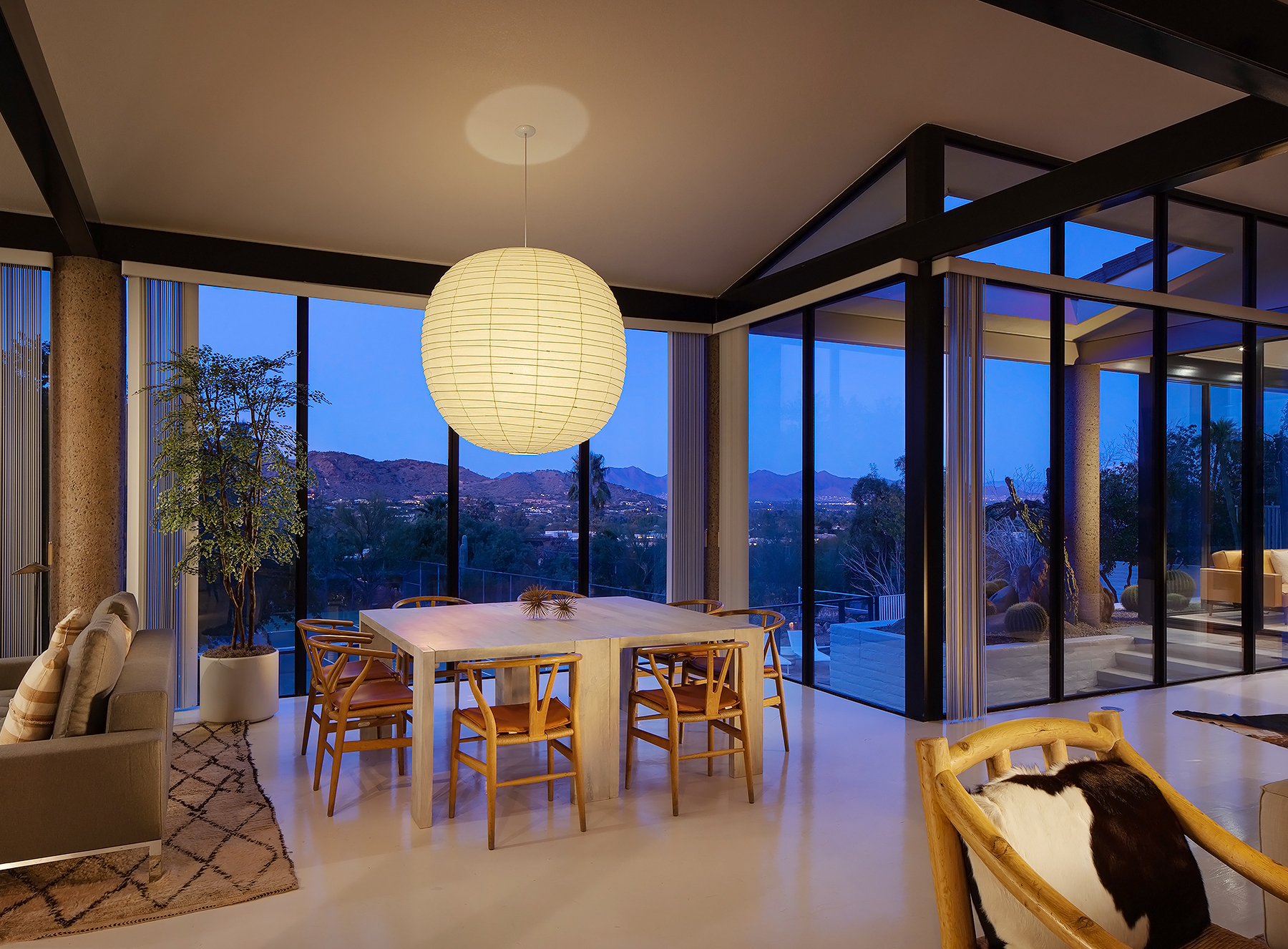 View of living room with dining table, custom chandelier and floor-to-ceiling windows.