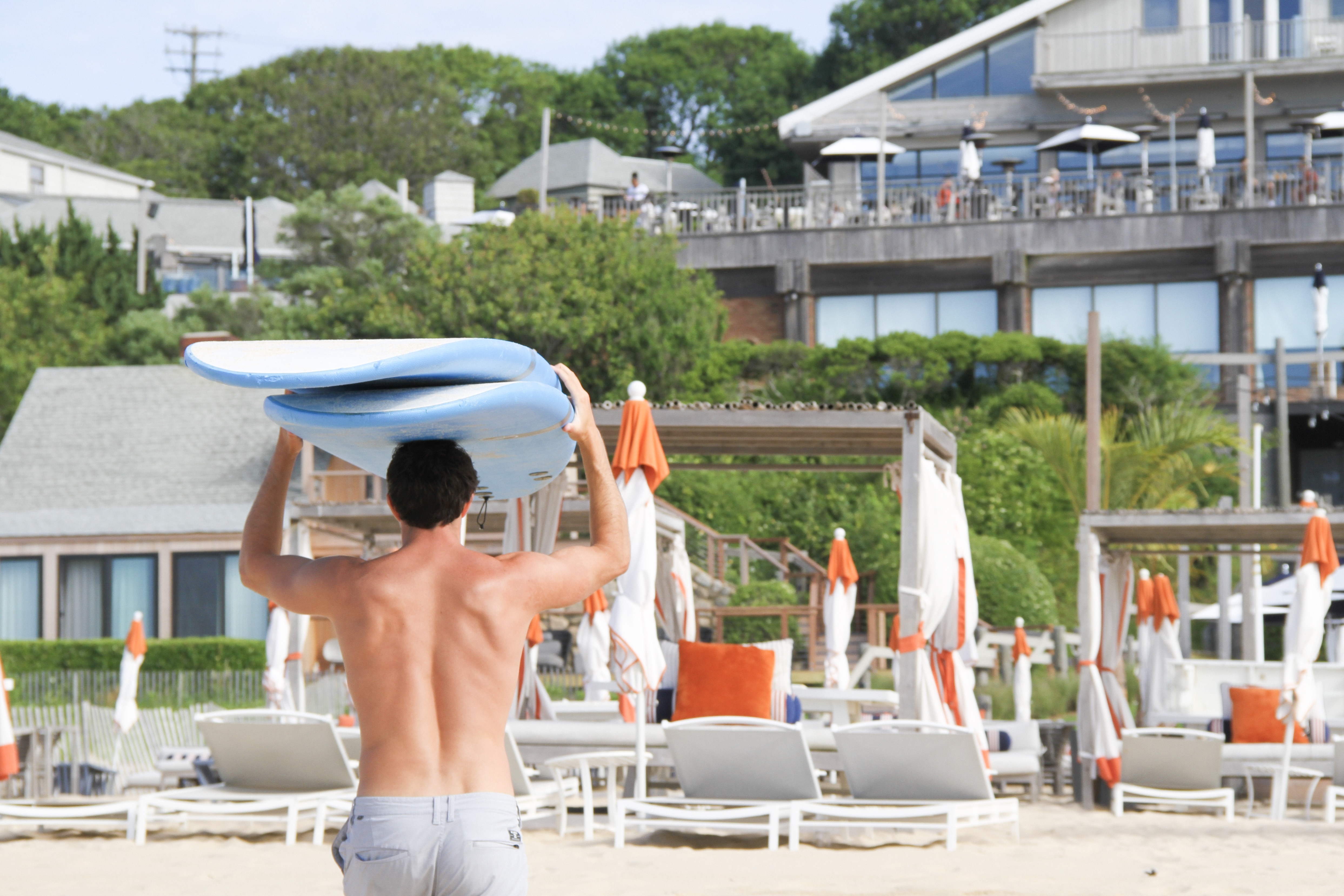 Man carrying surf board up the beach.