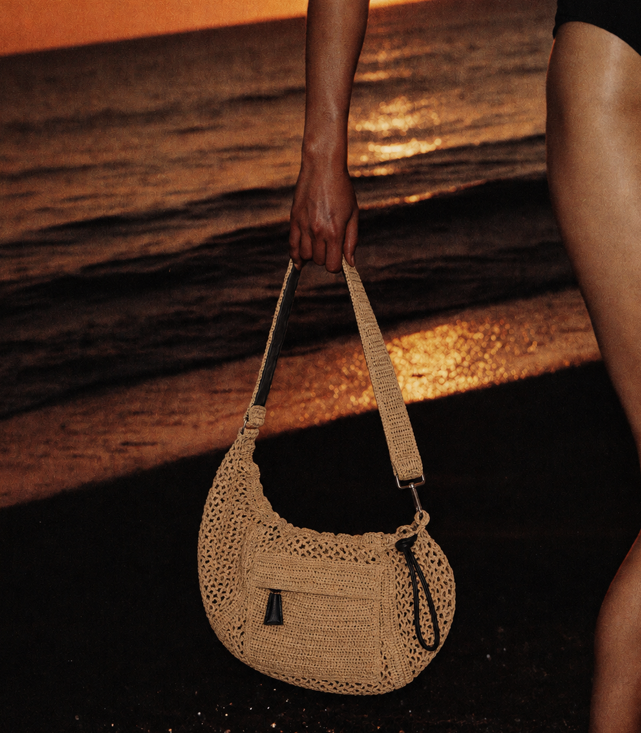 girl on the beach holding a purse at sunset