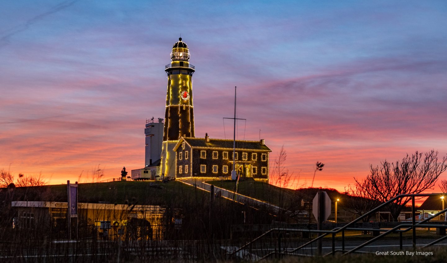Montauk Lighthouse with holiday lighting and colorful sunset.