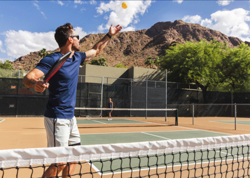 Man serving Pickleball to partner on Sanctuary's new outdoor Pickleball court.