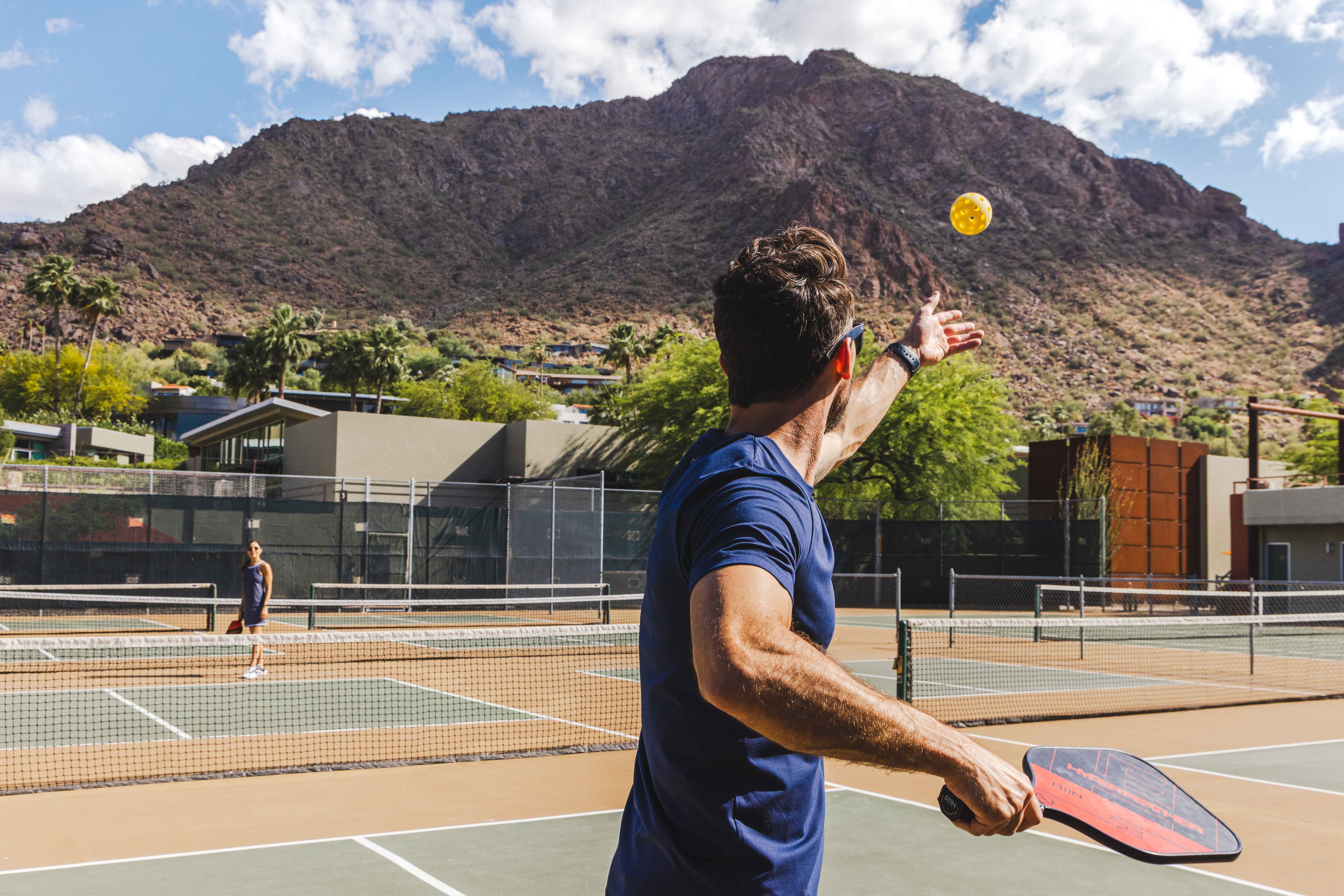 Man serving Pickleball to partner on Sanctuary's new outdoor Pickleball court.