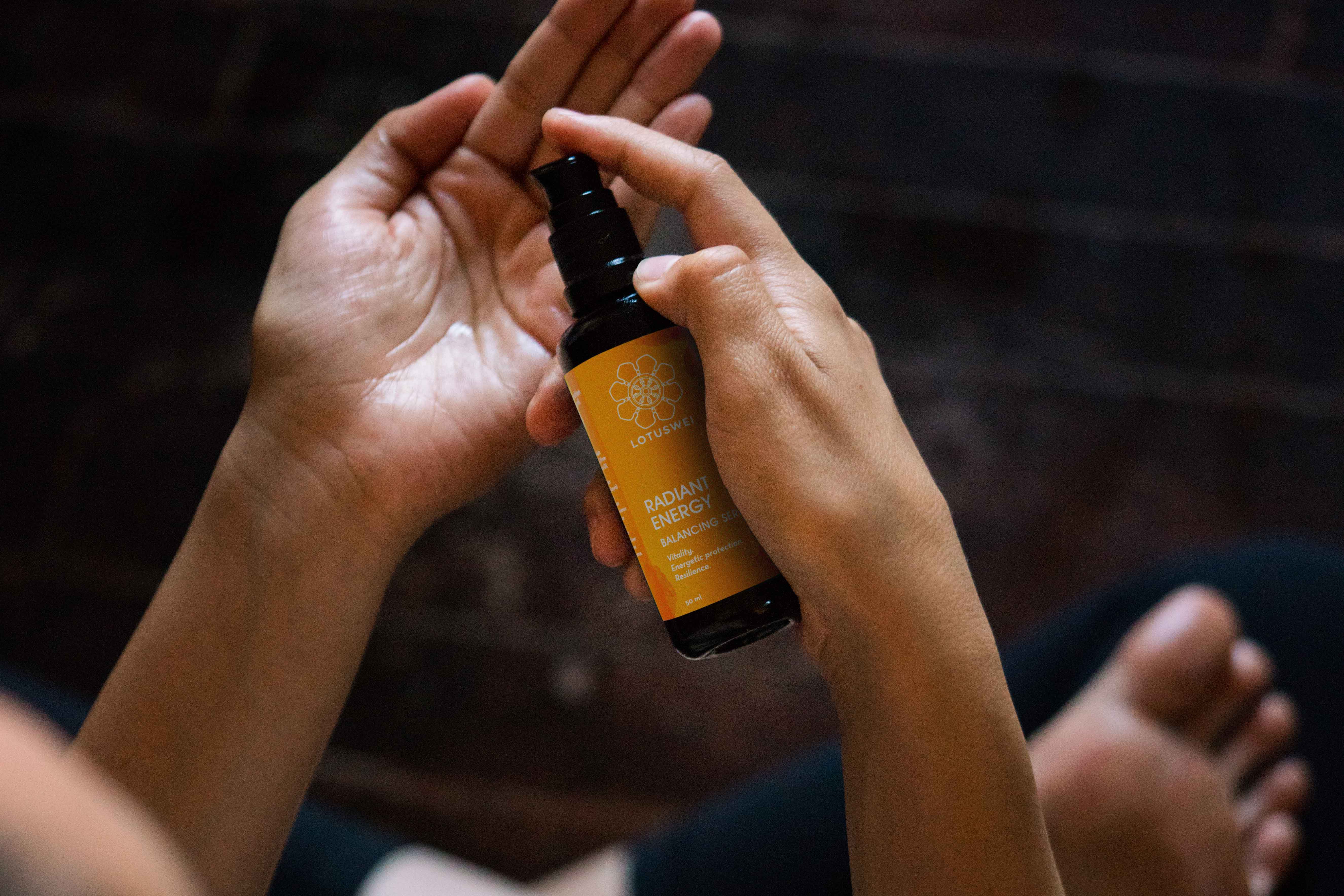 Woman spraying LOTUSWEI Radiant Energy onto open hand.