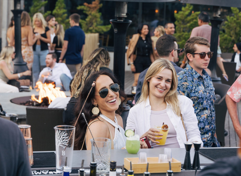 Two women smile for the camera in front of a crowd at The Firepit at Gurney's Montauk