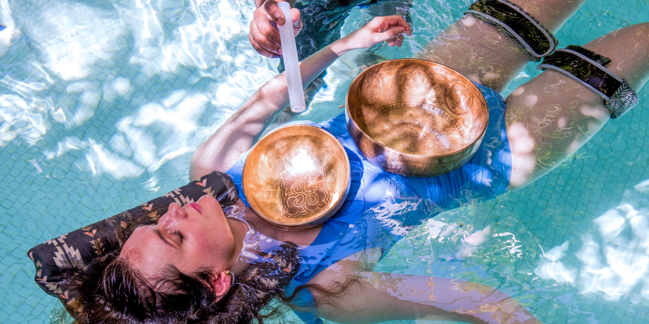 Woman floating in water as sound bowls are played during Watsu Aquatic Treatment and Sound Journey.