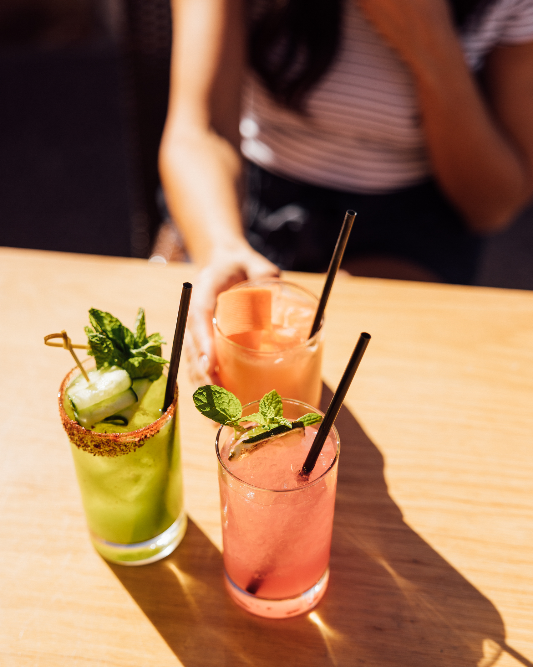 Woman sitting at table with a selection of spring cocktails.