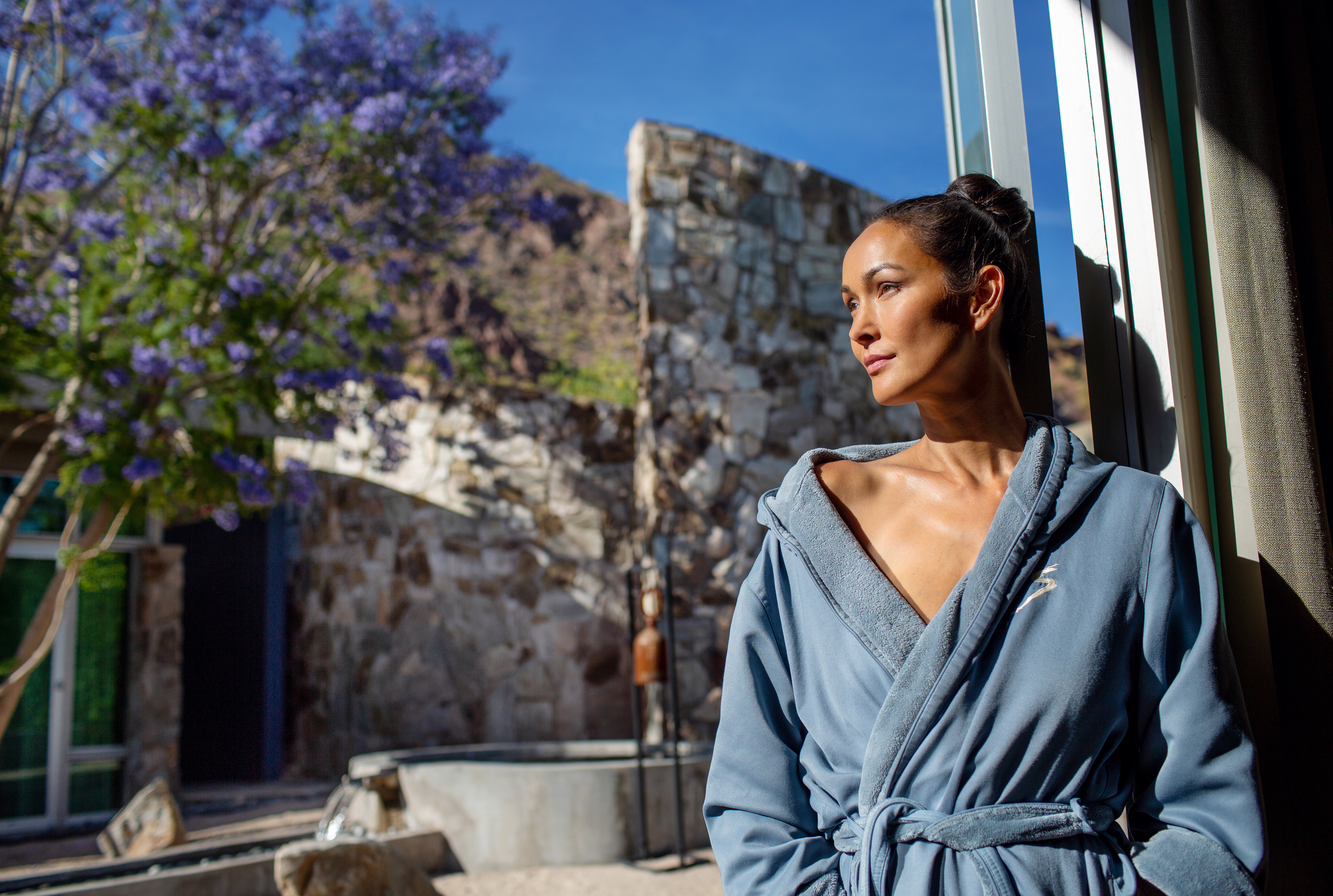 Woman in robe standing in doorway of indoor/outdoor treatment room at Sanctuary Spa.