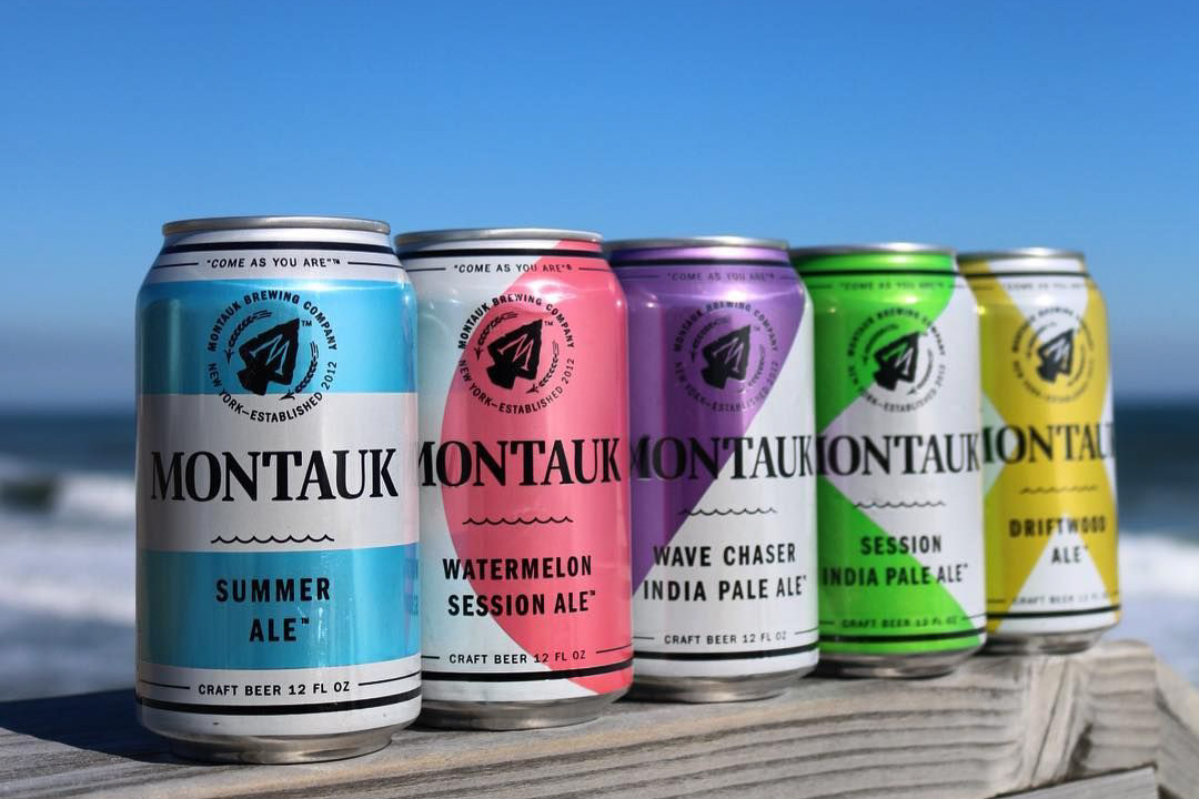 Assortment of Montauk Brewing Company beers displayed with beach in background.