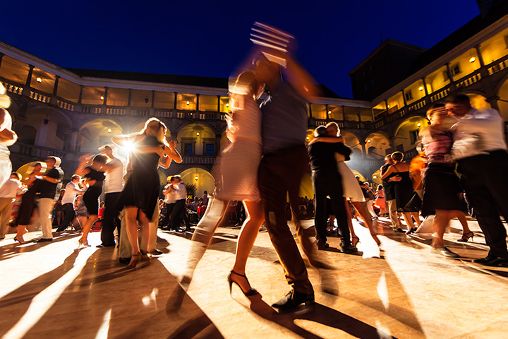 A woman and man dancing tango in a crowd at night.