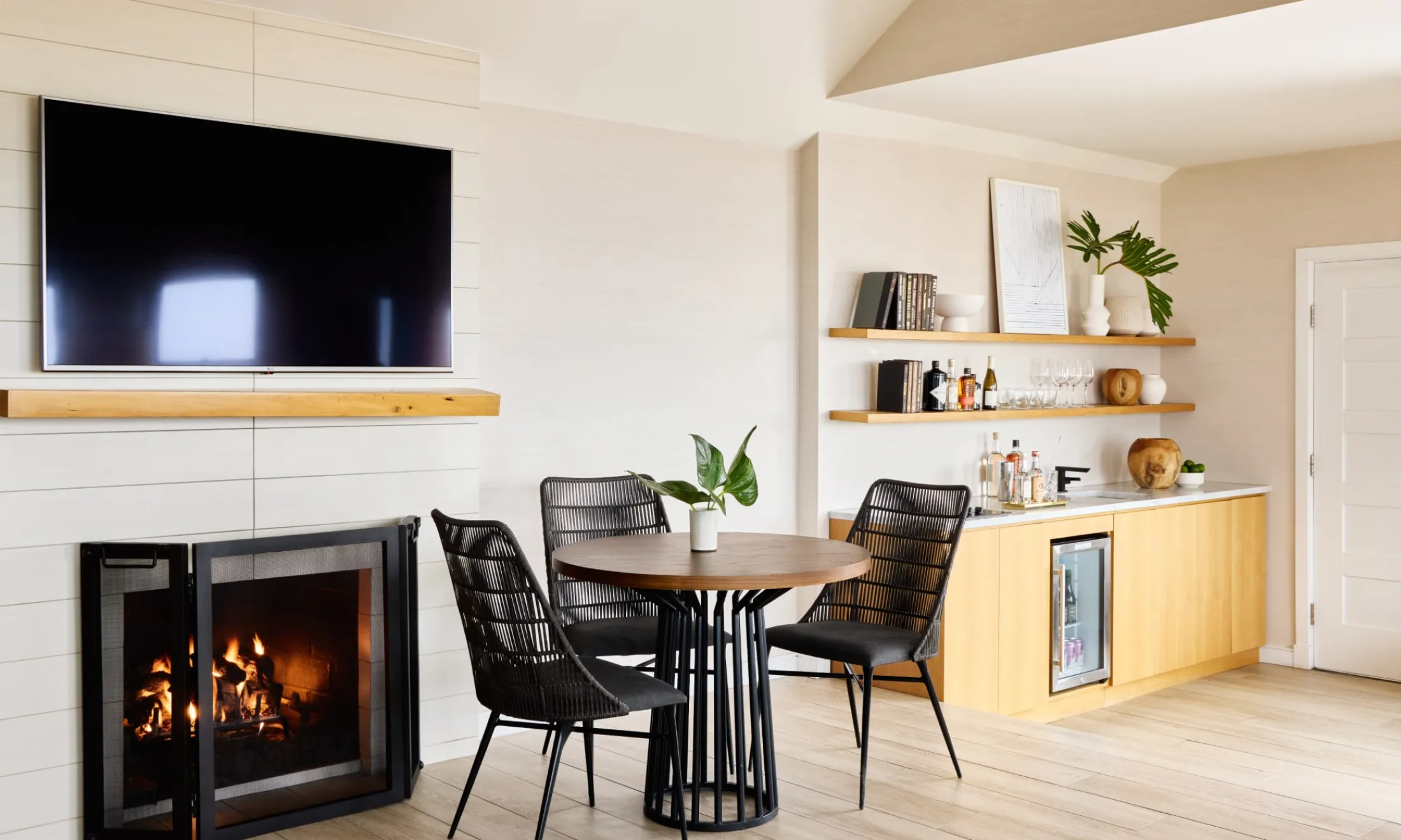A cozy dining area with a fireplace, TV, and wine fridge