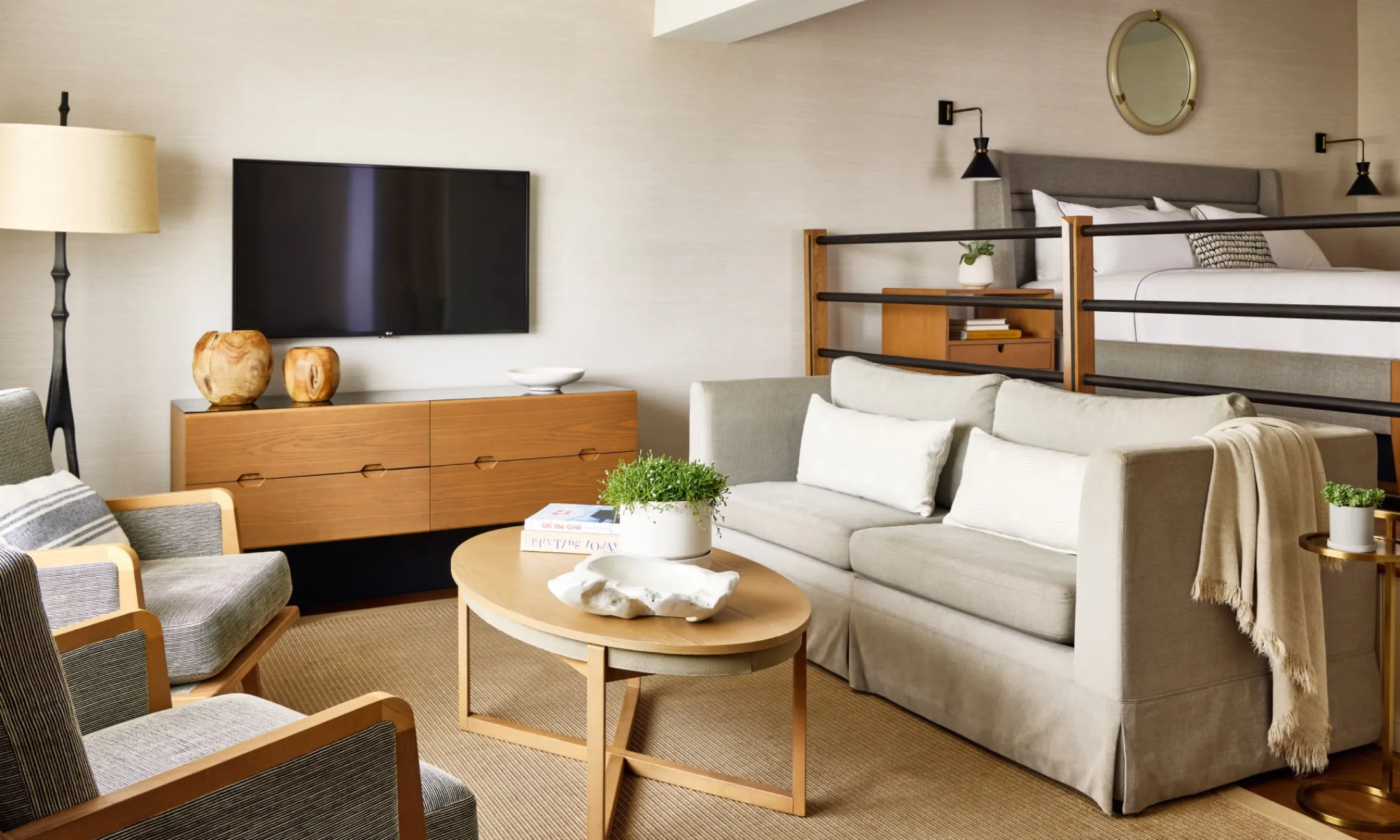A wide view of a hotel room with a sofa, coffee table, TV, bed, and chair.