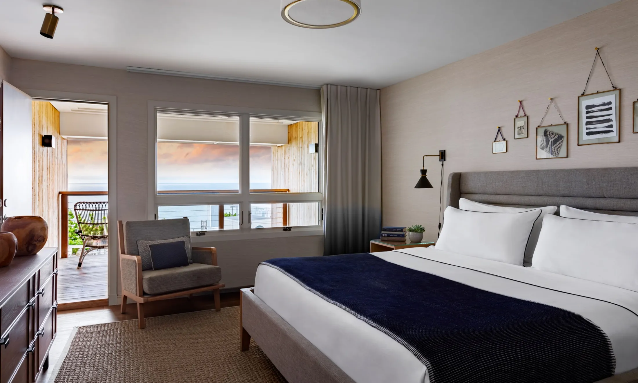 A hotel room with a bed, chair, and balcony overlooking the ocean.