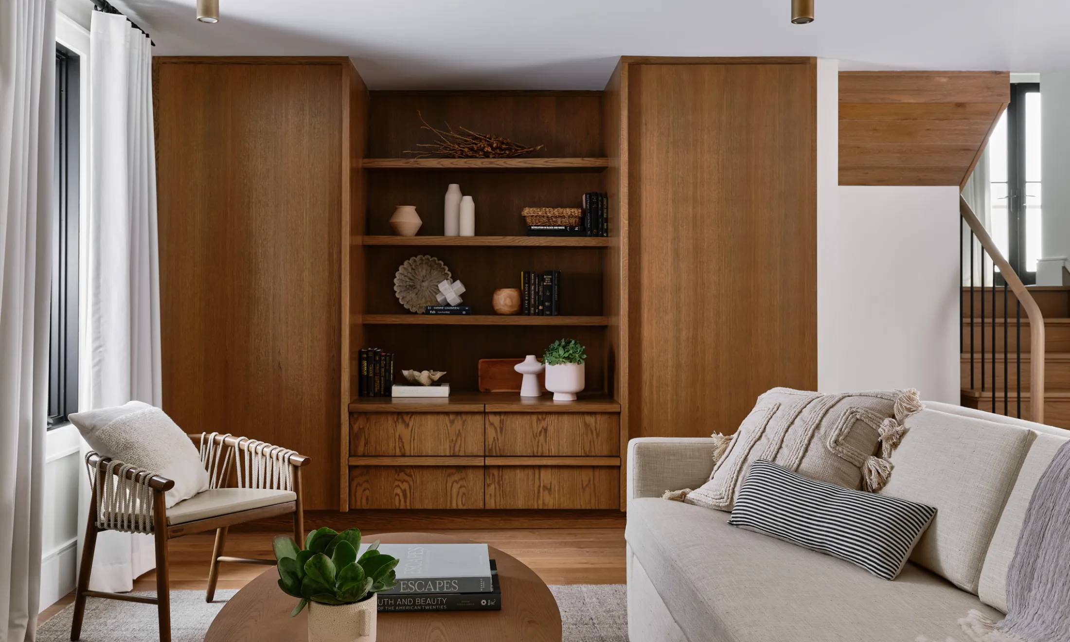 A living room with a large bookshelf, a beige sofa, a coffee table, and a chair.