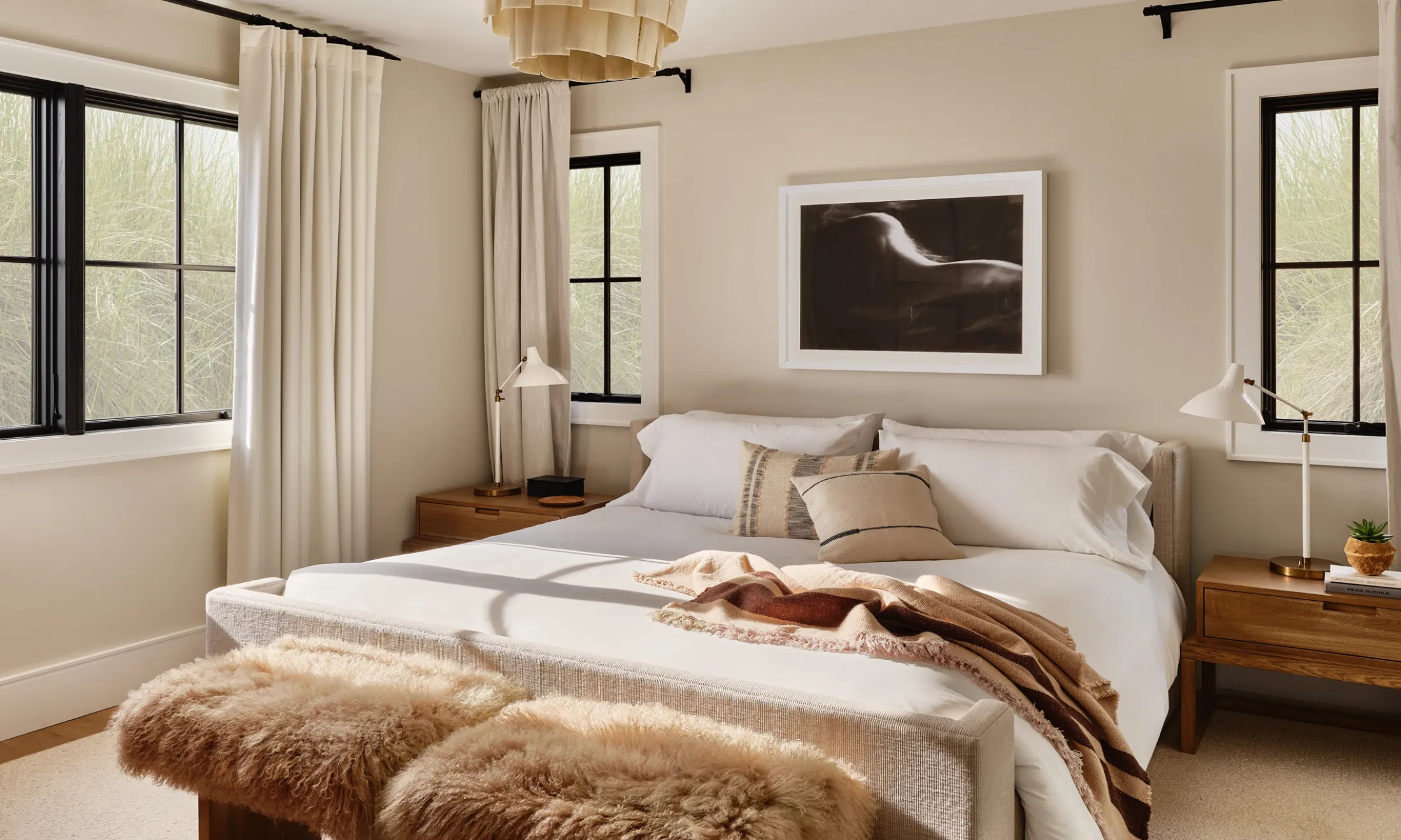 A wide view of a bedroom with a large bed, two nightstands, and a piece of artwork on the wall.