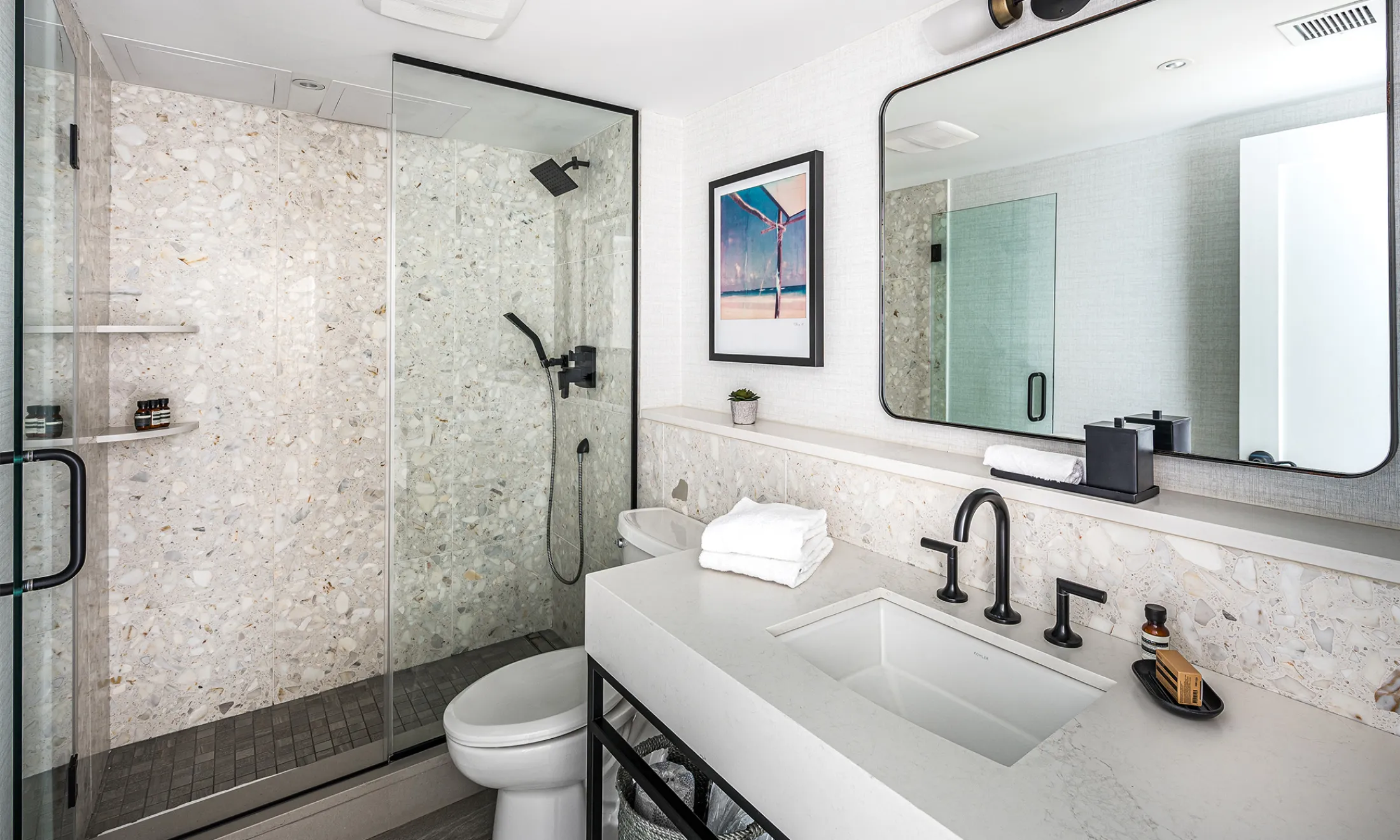 A modern bathroom with a shower, sink, toilet, and mirror