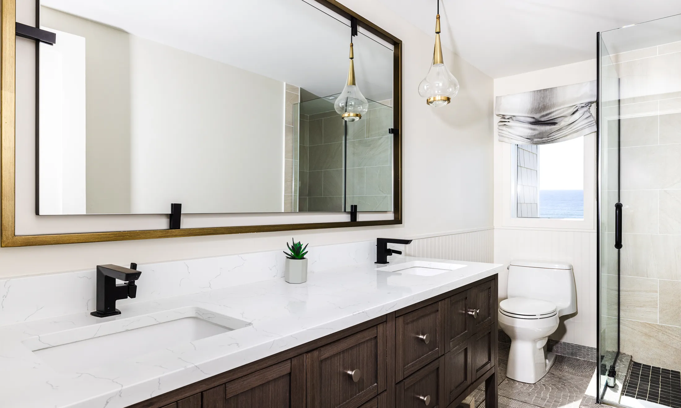 A modern bathroom with a double vanity, a toilet, and a shower