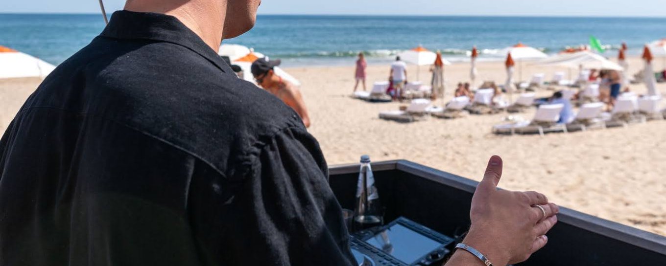 A DJ spins a turntable facing The Beach Club at Gurney's Montauk Resort