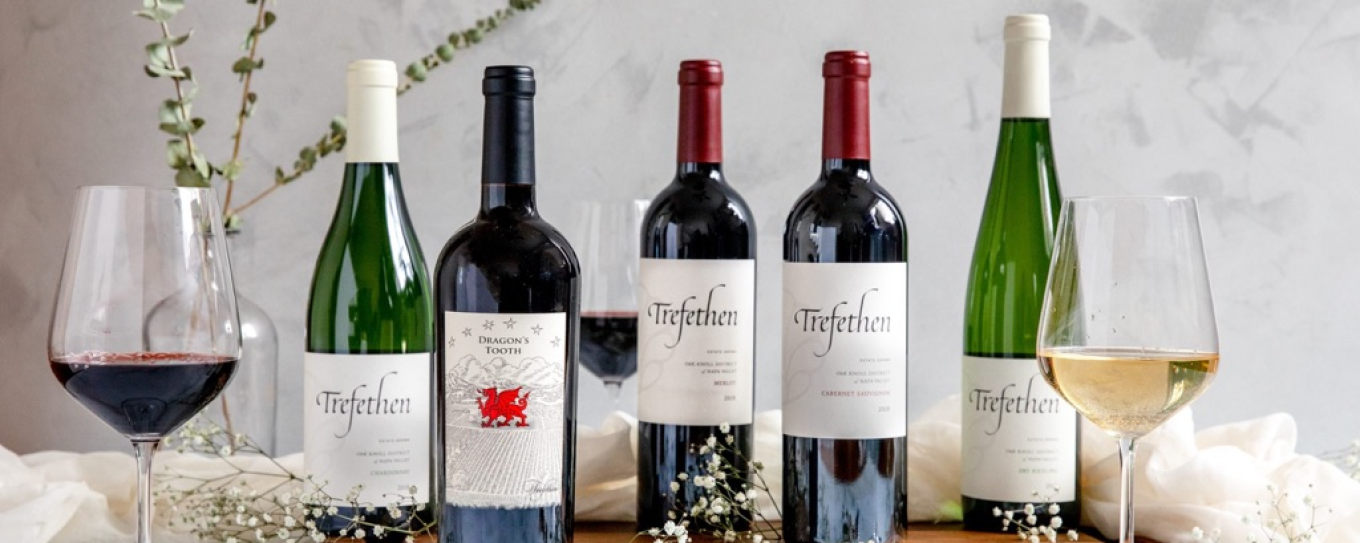 Bottles of wine with labels, accompanied by glasses of white and red wine, set on a marble table with delicate decorations.
