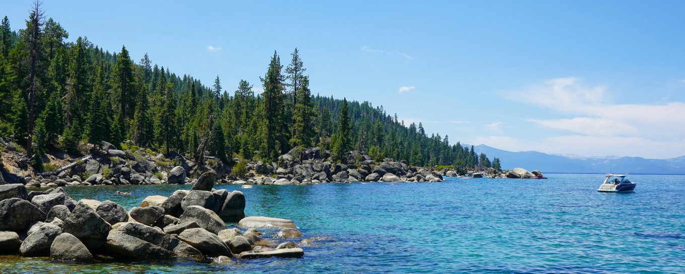 Image of Lake and side of land with rocks and trees. 