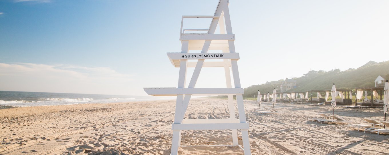 Lifeguard chair on a sunny beach, with a clear blue sky and the ocean to the left.