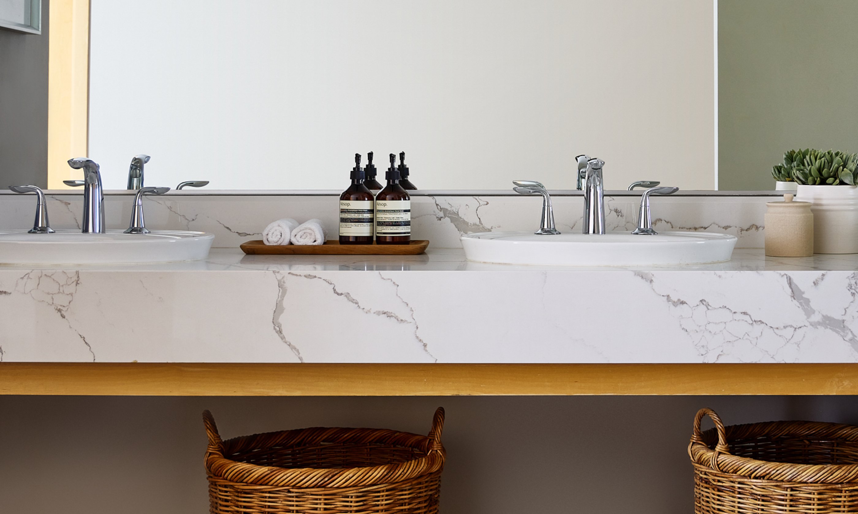 Marble top bathroom counter with two sinks, toiletries and vanity.