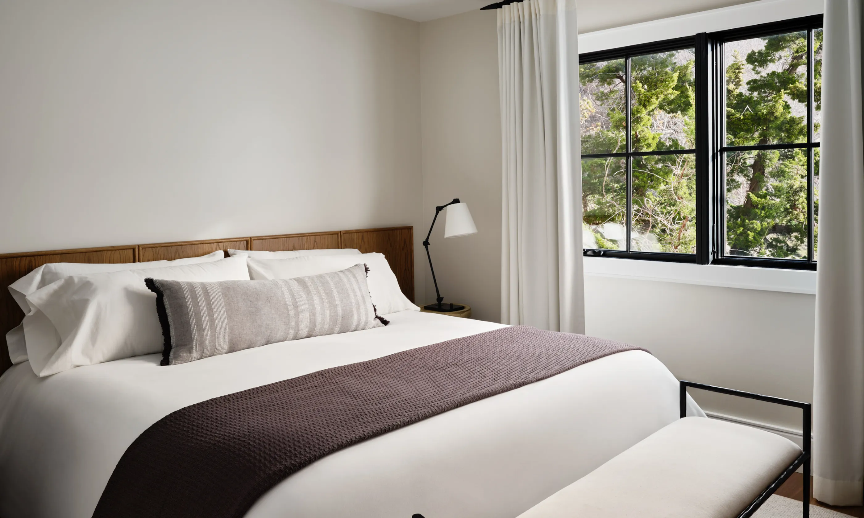 Bedroom with king bed, throw blanket, nightstand and window.