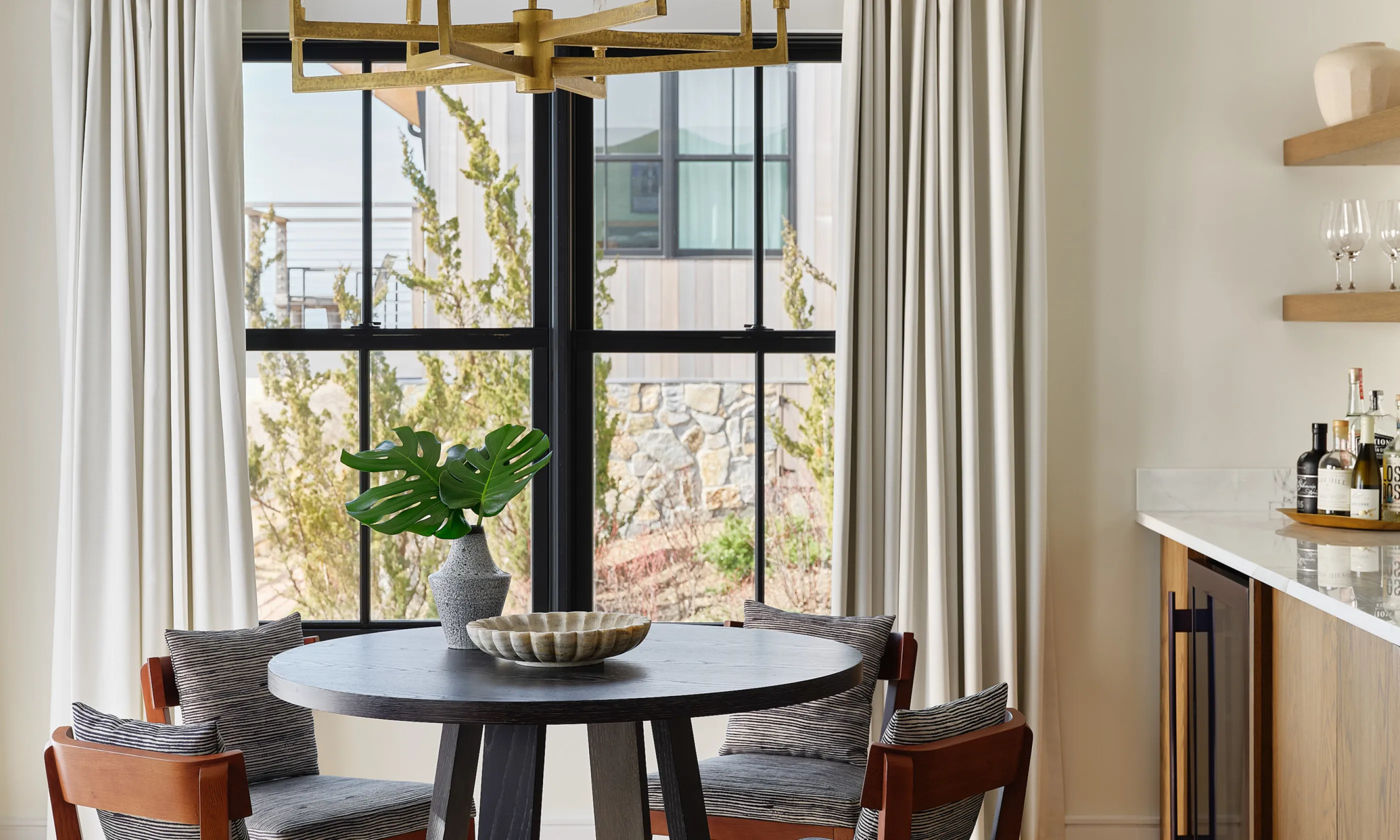 Dining table with chandelier and nearby wet bar.