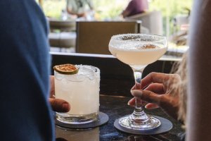 Man and woman holding hand-crafted cocktails at jade bar onyx-jade  drink rail