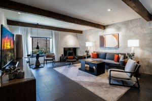 Mountain Suite living room with rug, accent wall, chair and couch, coffee table, fireplace and table and chairs overlooking view.