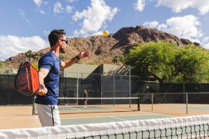 Couple playing Pickleball on Sanctuary's outdoor court with Camelback Mountain in background.