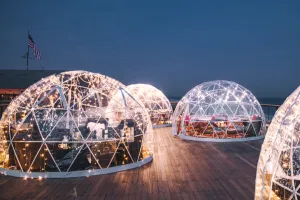 Warmly lit clear igloos against a dark blue evening sky at Gurney's Montauk Resort