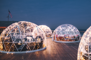 Warmly lit clear igloos against a dark blue evening sky at Gurney's Montauk Resort