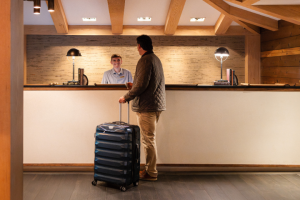 A man stands with luggage in front of the check-in desk at Gurney's Montauk Resort