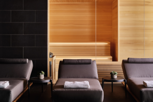 Three gray lounge chairs lined up with the sauna in the background at the Seawater Spa BathHouse