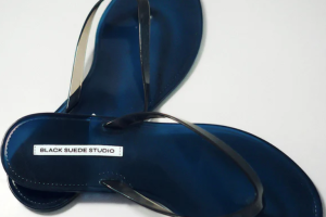 Dark blue flip-flops with thin black straps, label reads "BLACK SUEDE STUDIO."