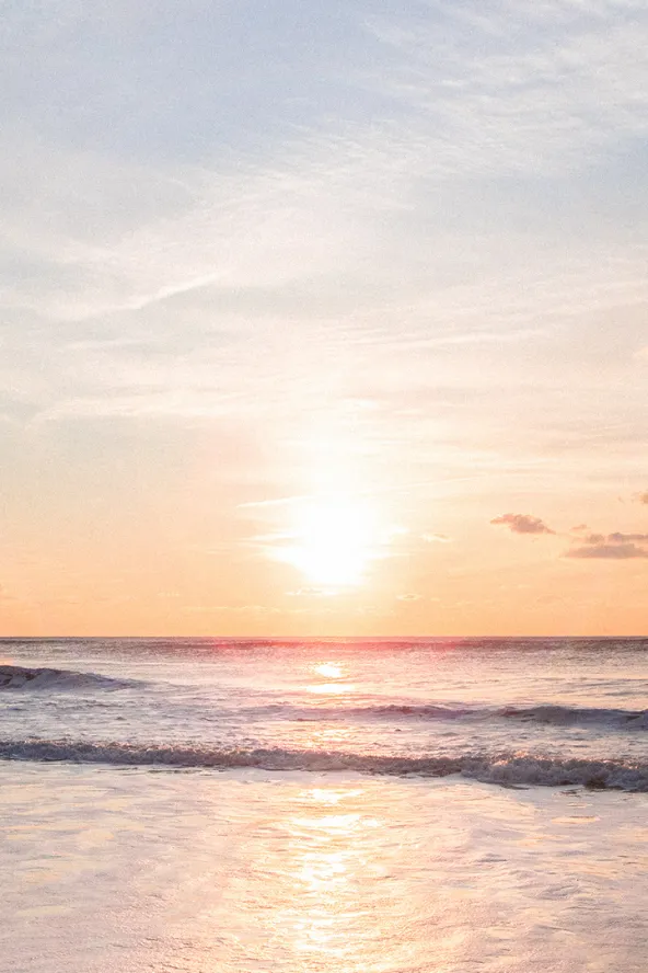 Sunset over a calm ocean, with soft pastel skies reflecting on gentle waves.