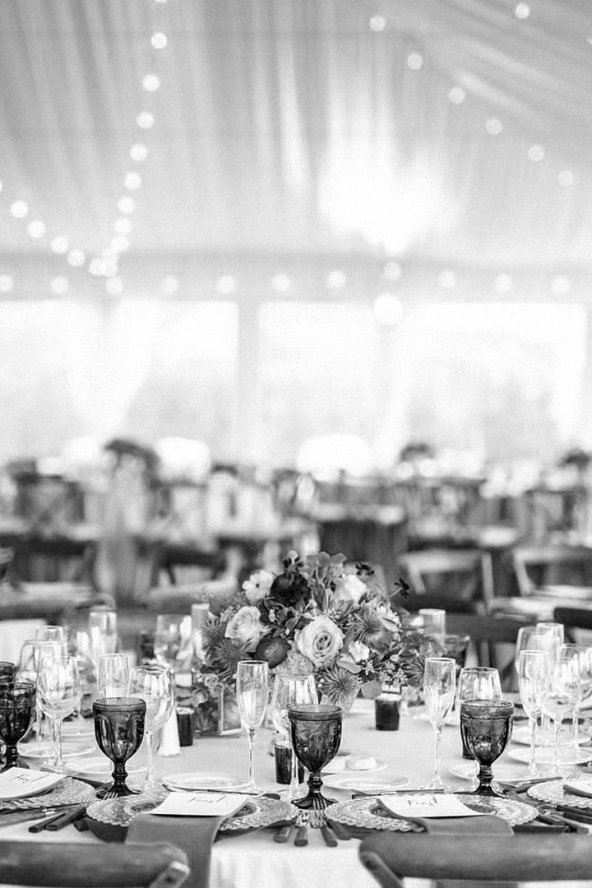 Elegant black-and-white banquet setting with floral centerpiece, glassware, and string lights overhead.