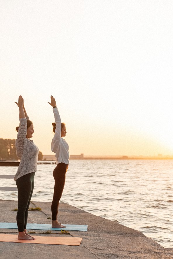 Two women doing yoga on the beach at sunrise