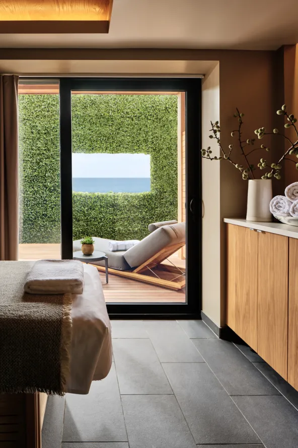 Seawater treatment suit with treatment table, outdoor patio with lounge chair and ocean view.